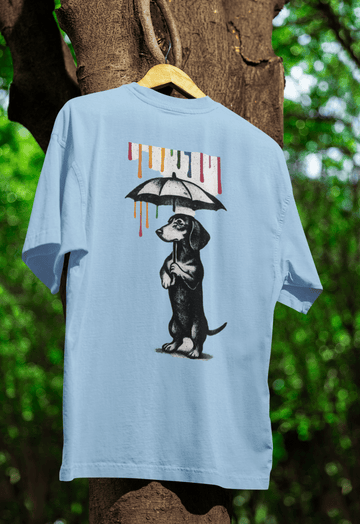 Hellblaues T-Shirt mit Dackel-Motiv unter Regenschirm und buntem Farbregen im Banksy-inspirierten Street-Art-Stil für Kunstliebhaber.