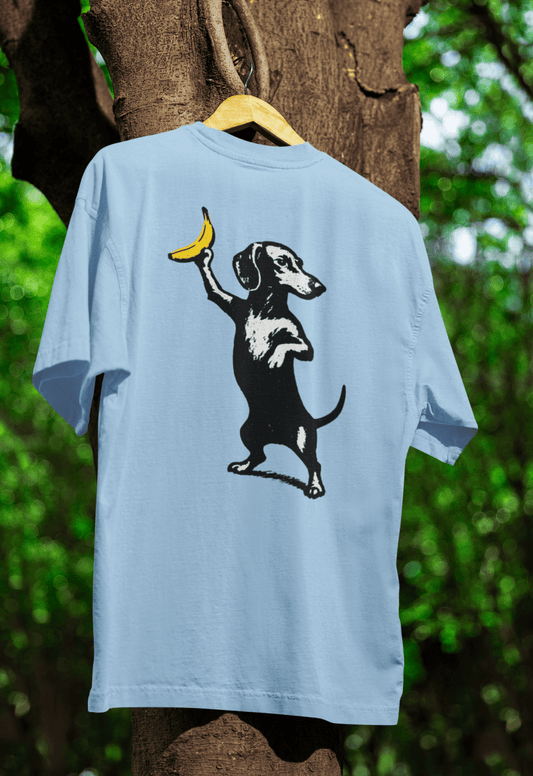 Hellblaues T-Shirt mit Dackel-Banane-Motiv im Street-Art-Stil für Hundefreunde und Kunstliebhaber.