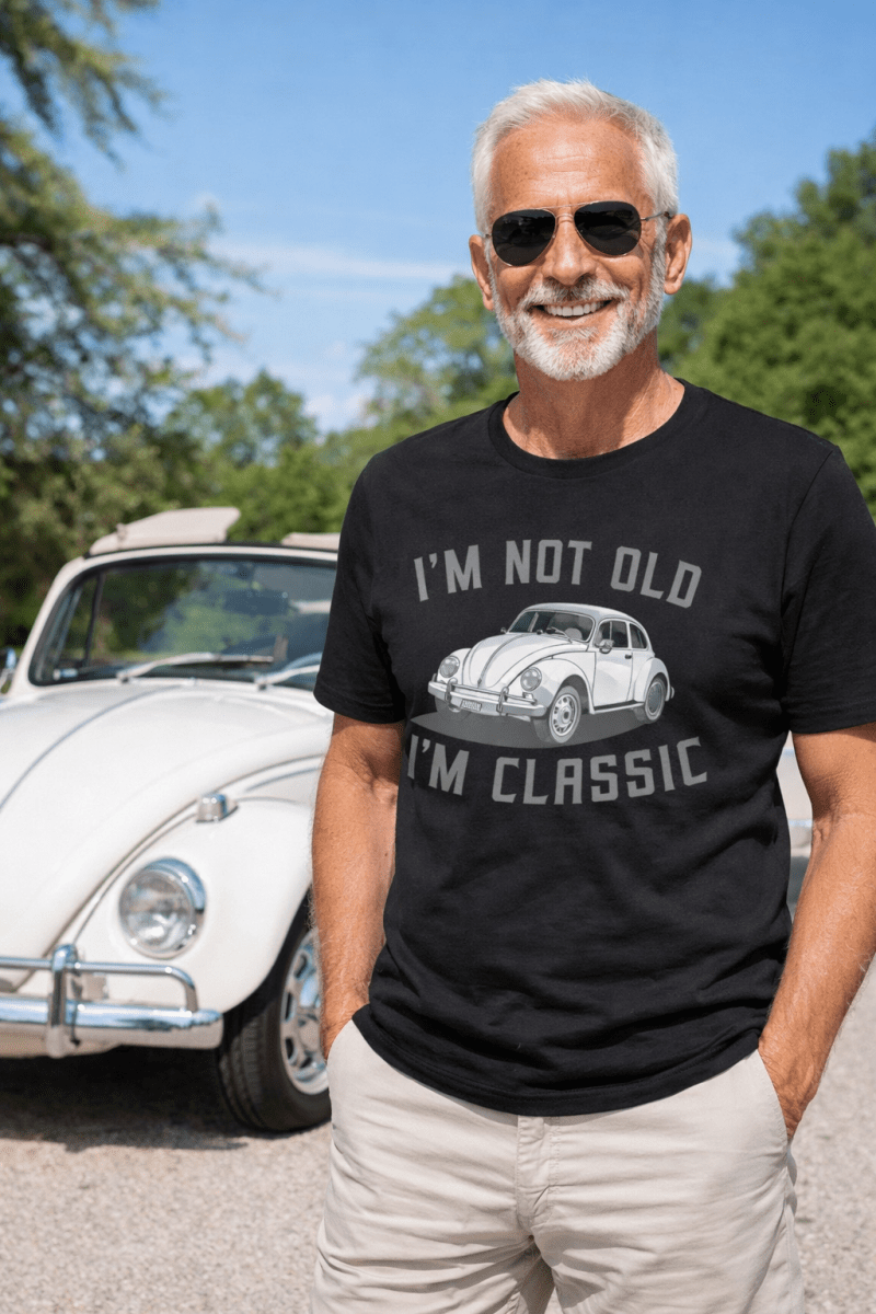 Mann mit Sonnenbrille vor weißem VW Käfer im „I'm not old, I'm classic“-Shirt – Schocktober-Sale –40 %