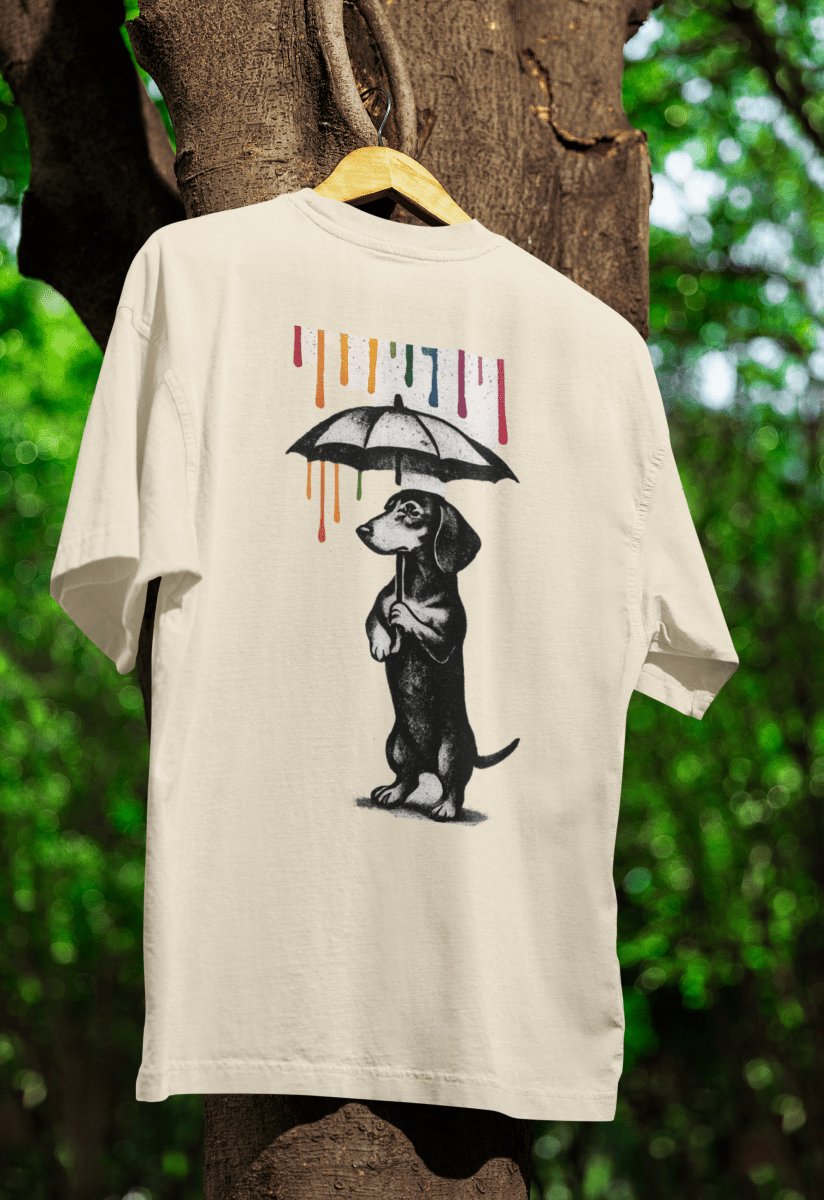 Cremefarbenes T-Shirt mit Dackel-Schriftzug Color-Rain im Banksy-inspirierten Street-Art-Stil mit buntem Farbregen für Hundeliebhaber.