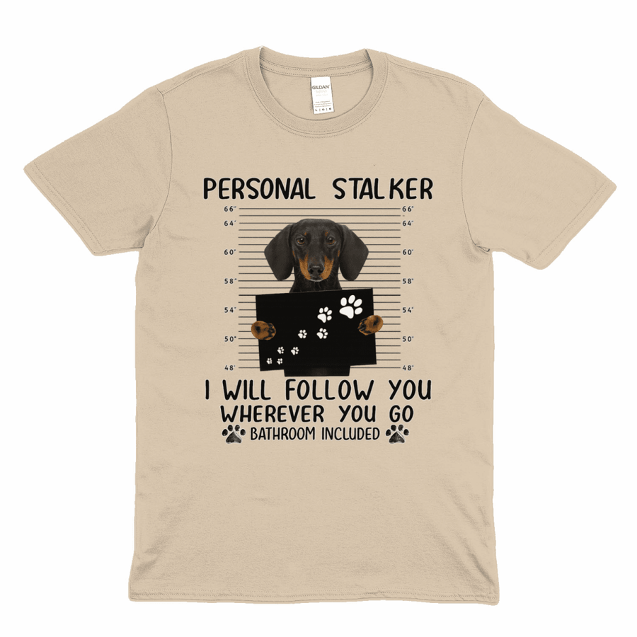 Beiges T-Shirt mit Dackel-Motiv und Schriftzug Personal-Stalker im humorvollen Comic-Stil fuer Hundeliebhaber.